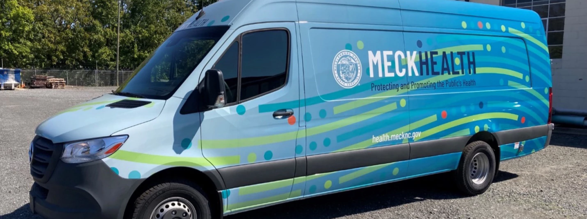 Public Health's Mobile Health Unit Side view of a light blue van with the County seal and the words Meck Health