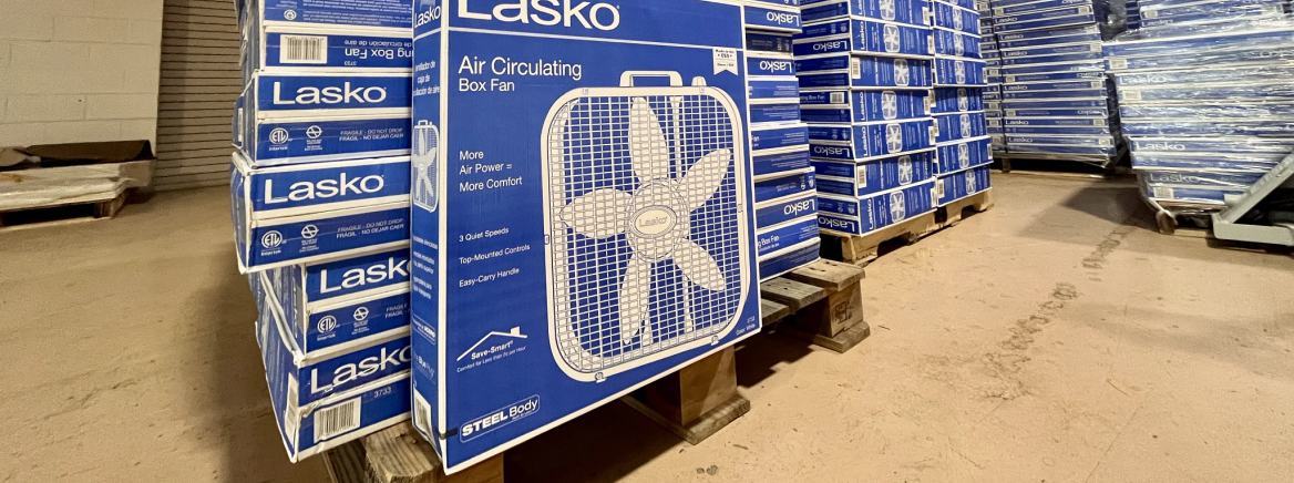 Box fan in warehouse A box fan positioned in front of several additional stacked fans in a warehouse
